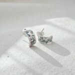 Aros de plata 950 con grabado floral sobre superficie mineral clara