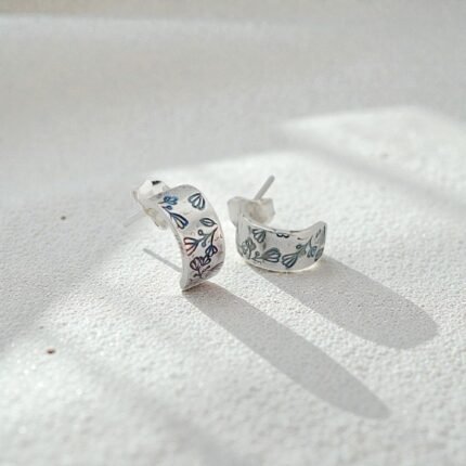 Aros de plata 950 con grabado floral sobre superficie mineral clara