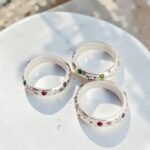 Tres anillos Eternal de Plataia en Plata 950 con 12 piedras naturales engastadas cada uno, fotografiados sobre una superficie clara con luz natural.