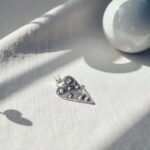 Colgante corazón de plata 950 con textura orgánica y detalles en relieve sobre tela clara
