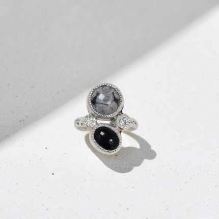 Anillo Mix en plata 950 libre de níquel con obsidiana nevada y ónix negro engastados en bisel, acompañado de una moissanita brillante y detalles grabados. Una composición contemporánea de contrastes suaves y oscuros