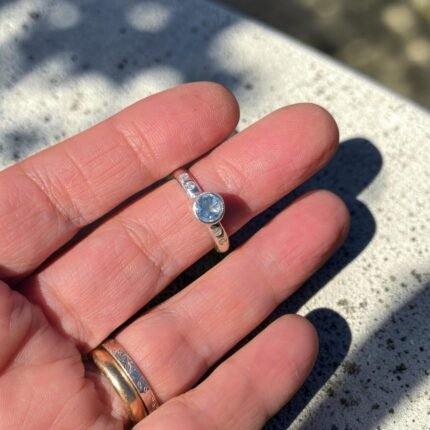 Anillo Axia topacio celeste puesto en la mano - Plataia joyería
