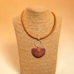 Colgante de plata 950 con picoyo natural y cordón textil mostaza en exhibidor, pieza única de Plataia