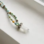 Collar de piedras naturales con turquesa tibetana, amazonita, ojo de tigre y bolitas de plata, con colgante de cuarzo cristal natural en bruto y engaste de plata hecho a mano.